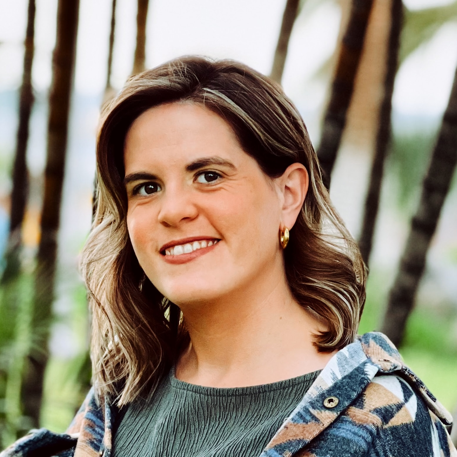 Smiling woman outdoors with flannel jacket and earrings
