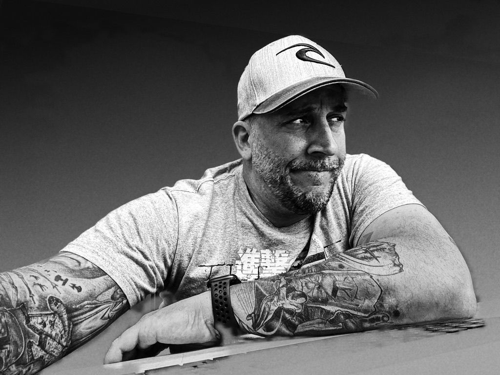 Man with tattoos and cap looking thoughtful